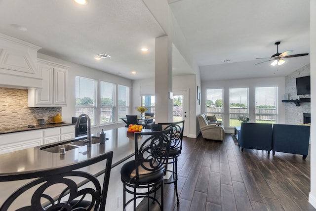 kitchen featuring ceiling fan, dark hardwood / wood-style flooring, tasteful backsplash, white cabinetry, and a fireplace