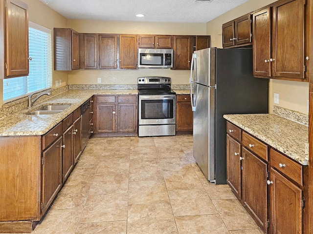 kitchen featuring light stone counters, stainless steel appliances, sink, and light tile patterned floors