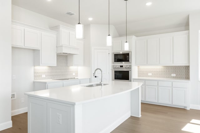 kitchen featuring black electric stovetop, visible vents, a sink, built in microwave, and oven