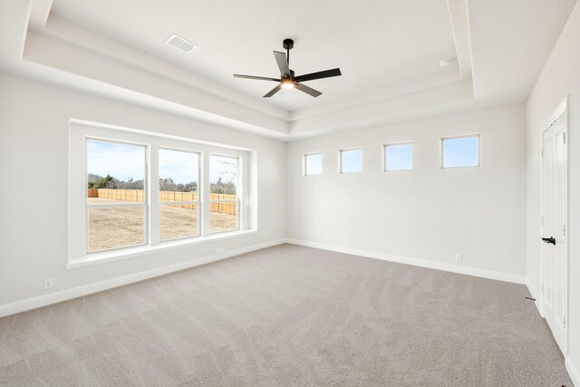 unfurnished room featuring carpet, baseboards, visible vents, and a raised ceiling