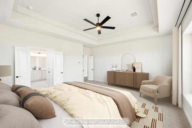 bedroom with light colored carpet, a raised ceiling, visible vents, and ensuite bath