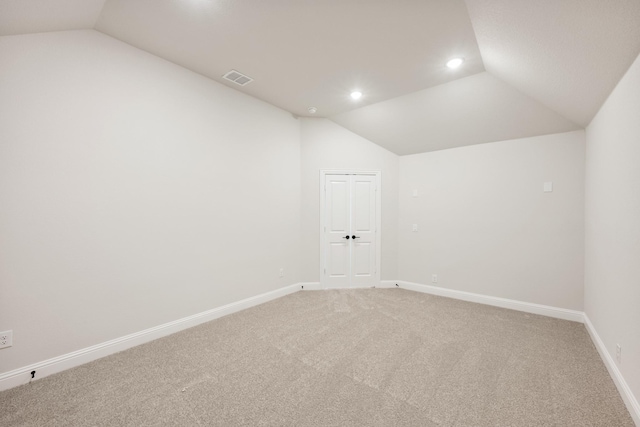 empty room with vaulted ceiling, recessed lighting, baseboards, and light colored carpet