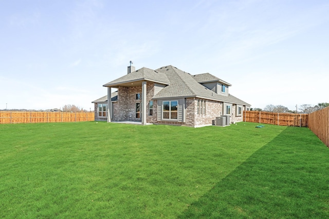 rear view of house with a shingled roof, central AC unit, a lawn, a fenced backyard, and brick siding