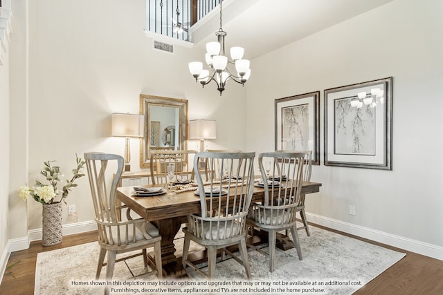 dining area featuring a high ceiling, wood-type flooring, and an inviting chandelier