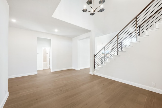 unfurnished living room featuring stairs, baseboards, and wood finished floors