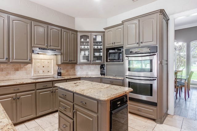 kitchen with light stone countertops, appliances with stainless steel finishes, tasteful backsplash, sink, and a center island