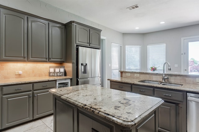 kitchen featuring decorative backsplash, appliances with stainless steel finishes, light stone countertops, and gray cabinetry