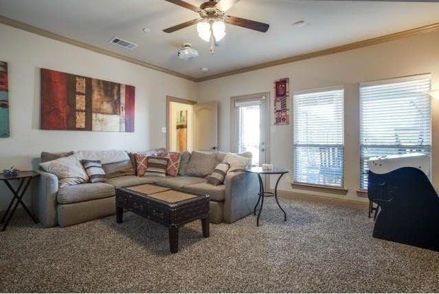 carpeted living room with ceiling fan and crown molding