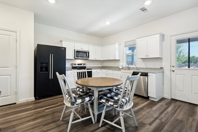 kitchen with appliances with stainless steel finishes, dark wood-type flooring, white cabinetry, and light stone countertops