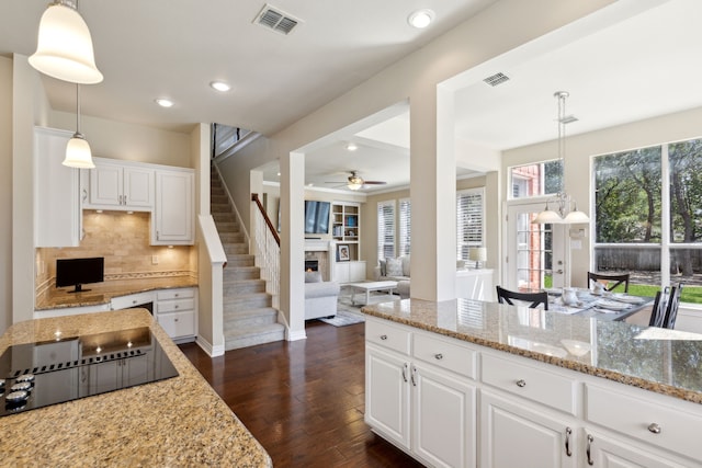 kitchen featuring pendant lighting, dark wood-type flooring, black electric stovetop, light stone counters, and white cabinetry