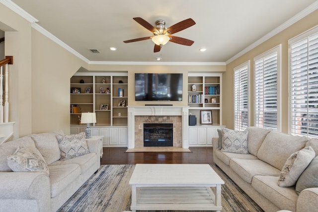 living room featuring a tile fireplace, ceiling fan, dark wood-type flooring, and ornamental molding