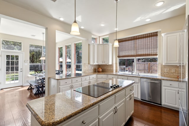 kitchen featuring dark hardwood / wood-style flooring, backsplash, black electric cooktop, dishwasher, and a kitchen island