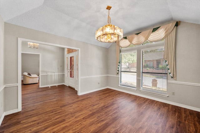 empty room featuring a textured ceiling, lofted ceiling, a chandelier, and hardwood / wood-style flooring