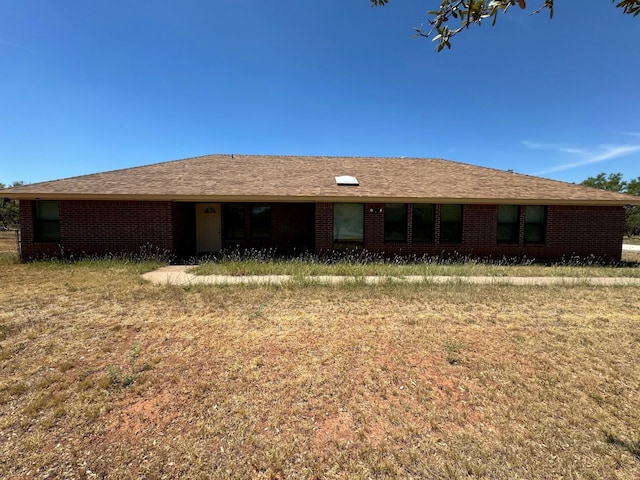 back of property with a shingled roof and brick siding