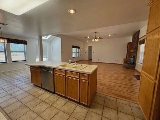 kitchen with dishwasher, sink, an island with sink, light wood-type flooring, and ceiling fan