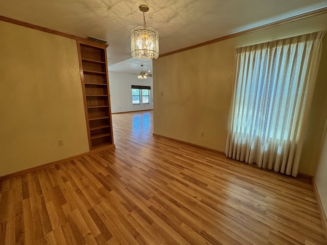 spare room featuring light hardwood / wood-style flooring, crown molding, and an inviting chandelier