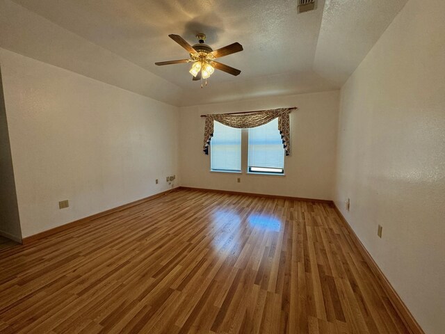 empty room with ceiling fan, wood-type flooring, a textured ceiling, and lofted ceiling