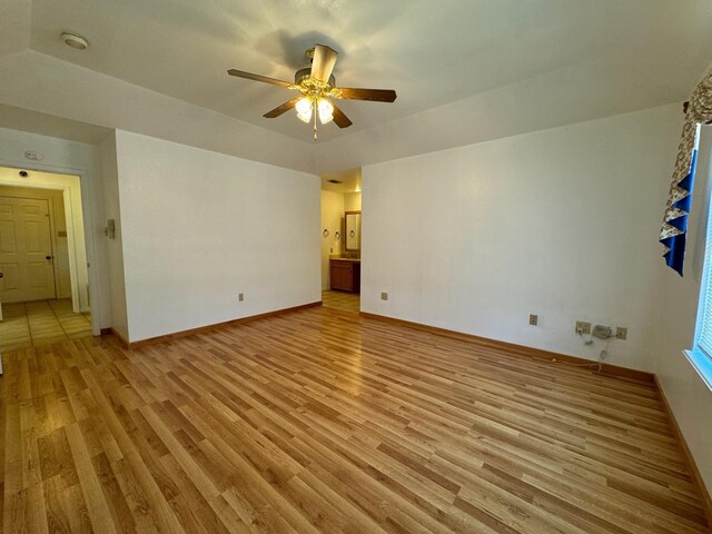 spare room with light wood finished floors, a ceiling fan, and baseboards