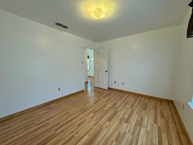 empty room with visible vents, light wood-style flooring, and baseboards