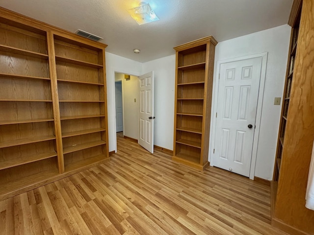 unfurnished bedroom with baseboards, visible vents, a textured ceiling, and light wood finished floors