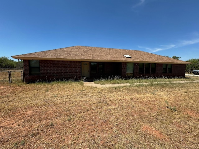 back of property featuring brick siding and roof with shingles