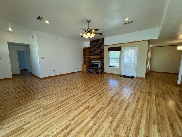 unfurnished living room with ceiling fan, light hardwood / wood-style flooring, brick wall, and a fireplace