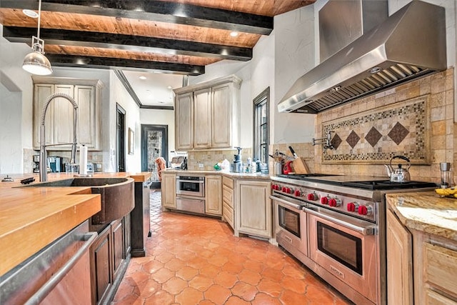 kitchen featuring wall chimney exhaust hood, appliances with stainless steel finishes, beam ceiling, tasteful backsplash, and hanging light fixtures