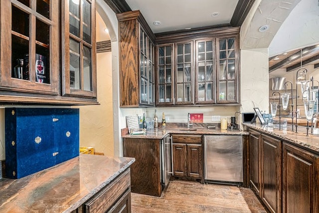 kitchen with light wood-type flooring, dark brown cabinets, stainless steel refrigerator, and light stone countertops