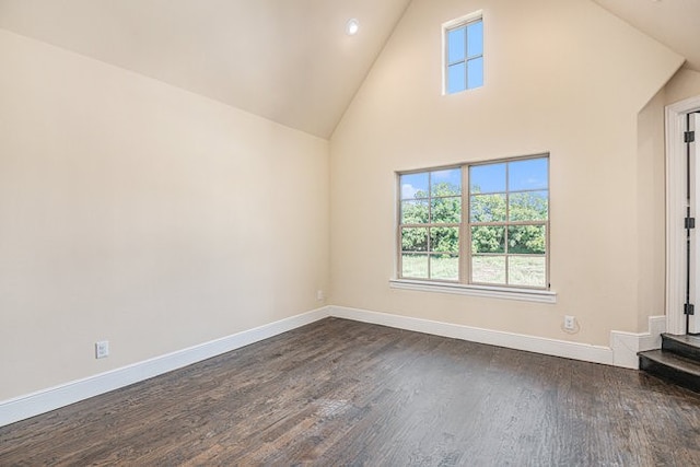 spare room featuring dark wood-type flooring and high vaulted ceiling