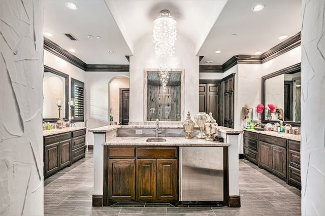 kitchen featuring an island with sink, sink, dark brown cabinetry, and an inviting chandelier