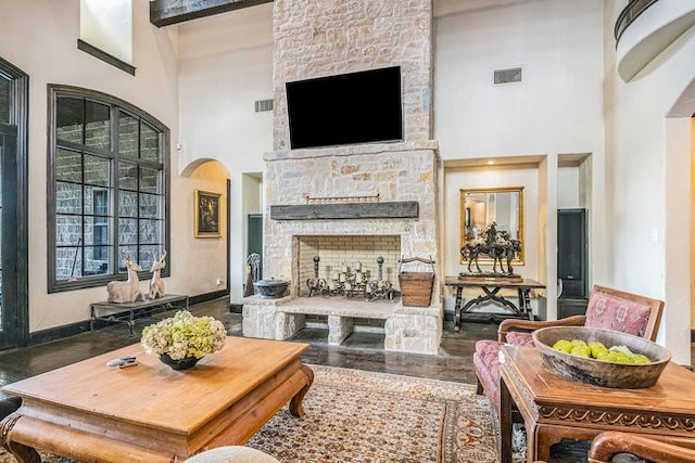 living room with a towering ceiling and a stone fireplace