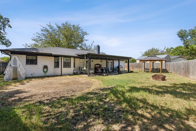 rear view of property with a patio, an outdoor fire pit, a gazebo, and a yard