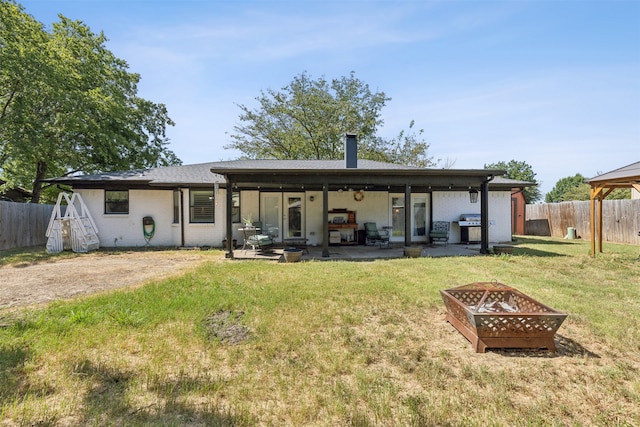 back of house with an outdoor fire pit, a patio, and a lawn