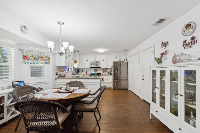 dining area with sink, a notable chandelier, and dark hardwood / wood-style floors