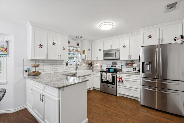 kitchen with appliances with stainless steel finishes, white cabinets, and dark hardwood / wood-style floors