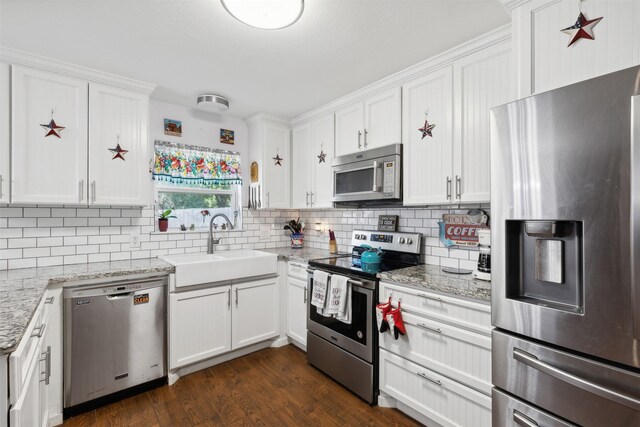 kitchen featuring dark hardwood / wood-style flooring, decorative backsplash, white cabinetry, and appliances with stainless steel finishes