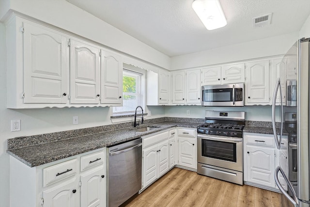 kitchen with sink, light wood-type flooring, a textured ceiling, white cabinetry, and stainless steel appliances