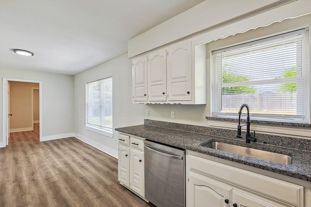 kitchen featuring sink, stainless steel dishwasher, dark stone counters, light hardwood / wood-style floors, and white cabinets