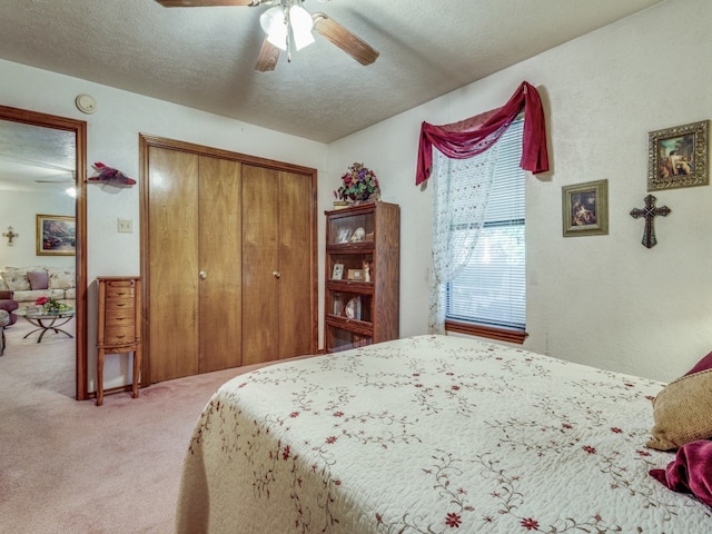 bedroom with ceiling fan, a closet, a textured ceiling, and carpet floors