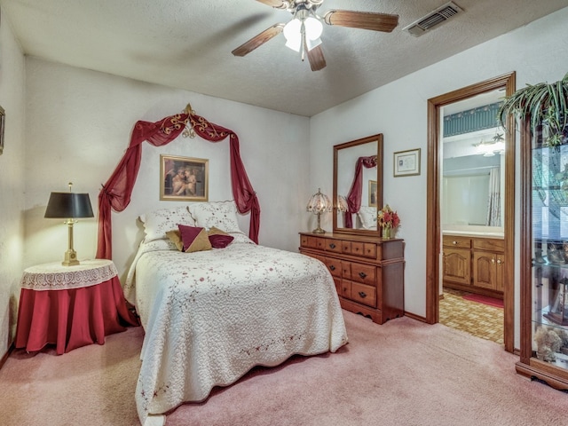 bedroom with ceiling fan, a textured ceiling, ensuite bath, and light colored carpet