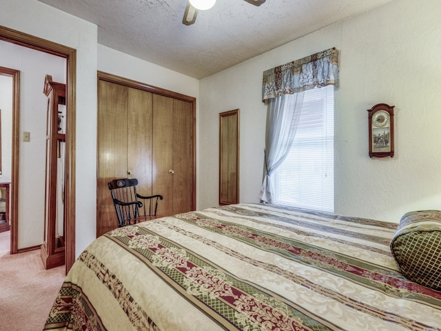 bedroom with light colored carpet, a closet, a textured ceiling, and ceiling fan