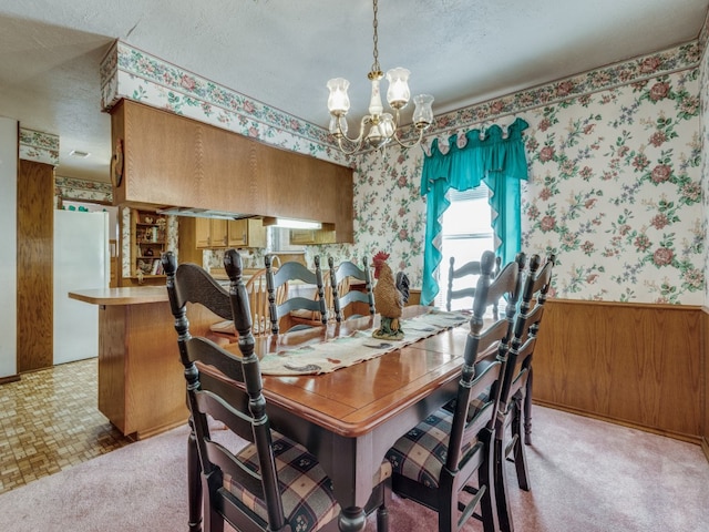 dining room featuring light colored carpet, a textured ceiling, and a chandelier