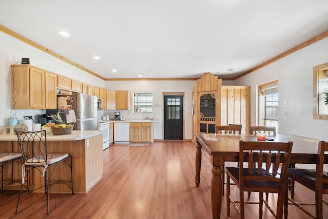 kitchen with light wood-type flooring, a healthy amount of sunlight, white appliances, and light brown cabinetry