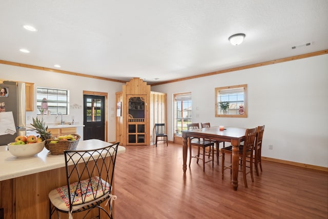 dining area with hardwood / wood-style floors, sink, and crown molding