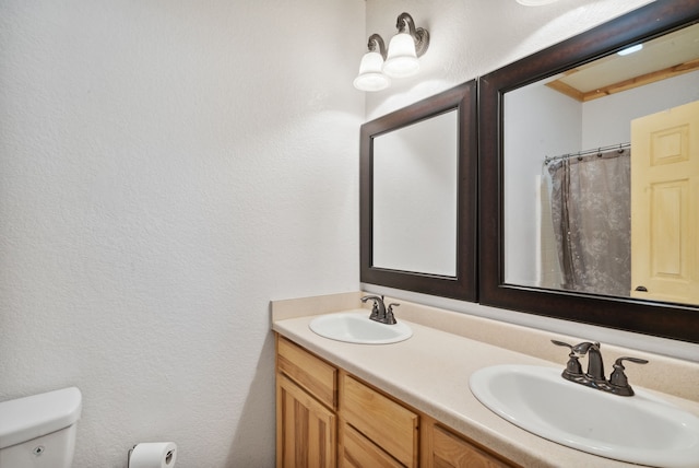 bathroom featuring toilet, crown molding, and double sink vanity