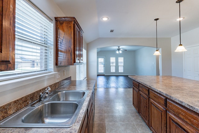 kitchen with ceiling fan, tile patterned flooring, hanging light fixtures, vaulted ceiling, and sink