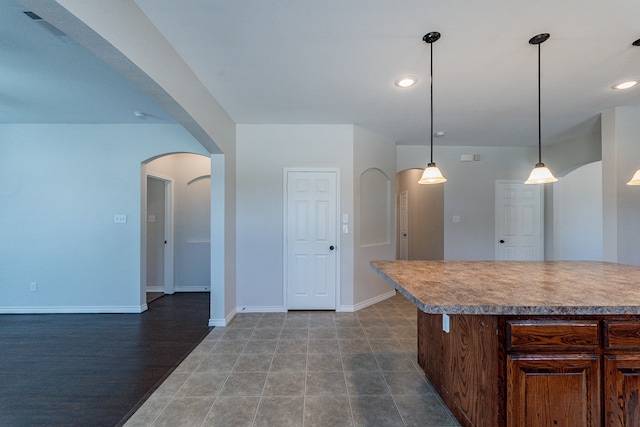 kitchen with a breakfast bar, dark wood-type flooring, pendant lighting, and a kitchen island