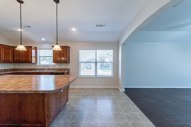 kitchen with light tile patterned floors, vaulted ceiling, sink, and pendant lighting