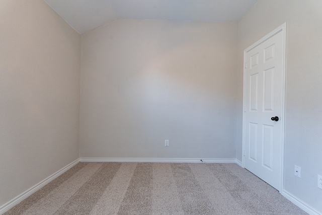 carpeted spare room with lofted ceiling