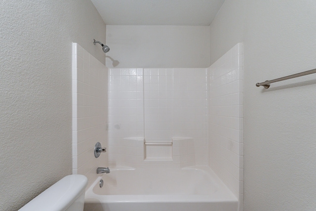 bathroom with toilet and tiled shower / bath combo